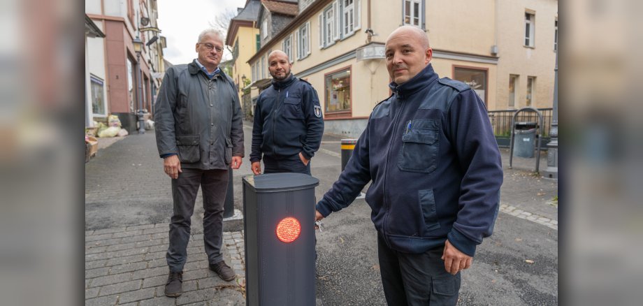 Der Schlüssel passt, der Poller senkt sich – es funktioniert! Im Beisein von Bürgermeister Christoph König und Jamal El Younchi von der Ordnungspolizei (v.li.) macht Christopher Dietz, hauptamtlicher Gerätewart der Kronberger Feuerwehren (re.), die erfolgreiche Probe aufs Exempel.